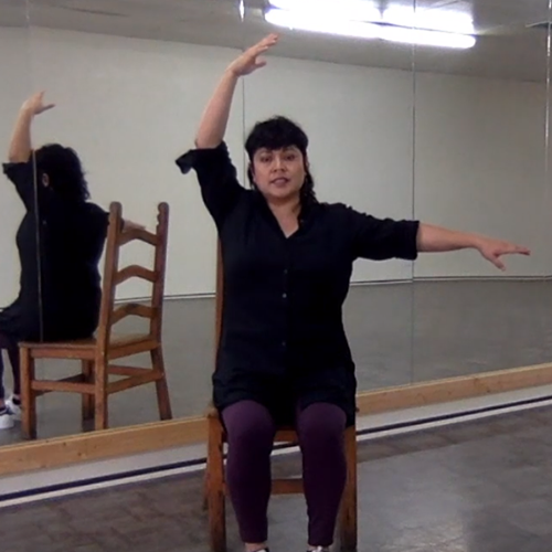 Dance instructor sitting in chair exercising arms