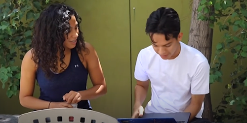 Two students with laptop outside